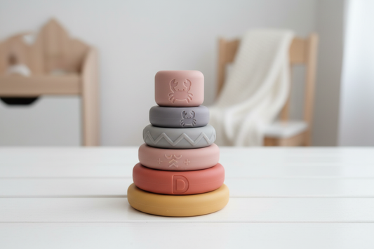 Colorful soft silicone baby stacking rings on white wooden surface with natural light